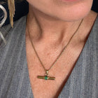 Woman wearing a gray sleeveless top with a necklace and earrings.