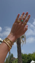 Three gold rings on a hand. One containing turquoise stone